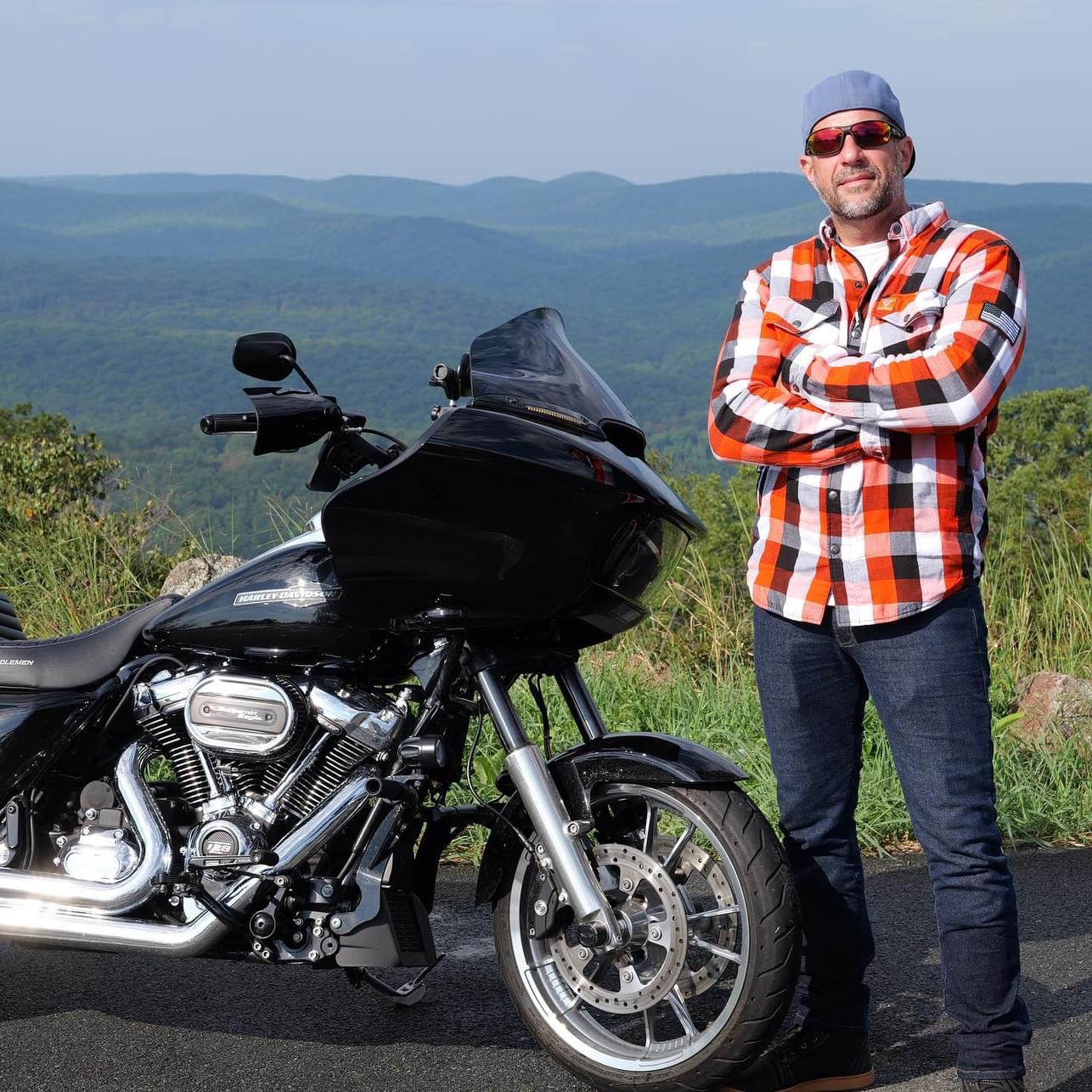 Rider-In-Red-Black-White-Checkered-Shirt-Stends-Next-To-Motorcycle